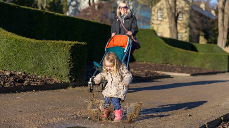 A little girl splashes in puddles at Wentworth Castle Gardens